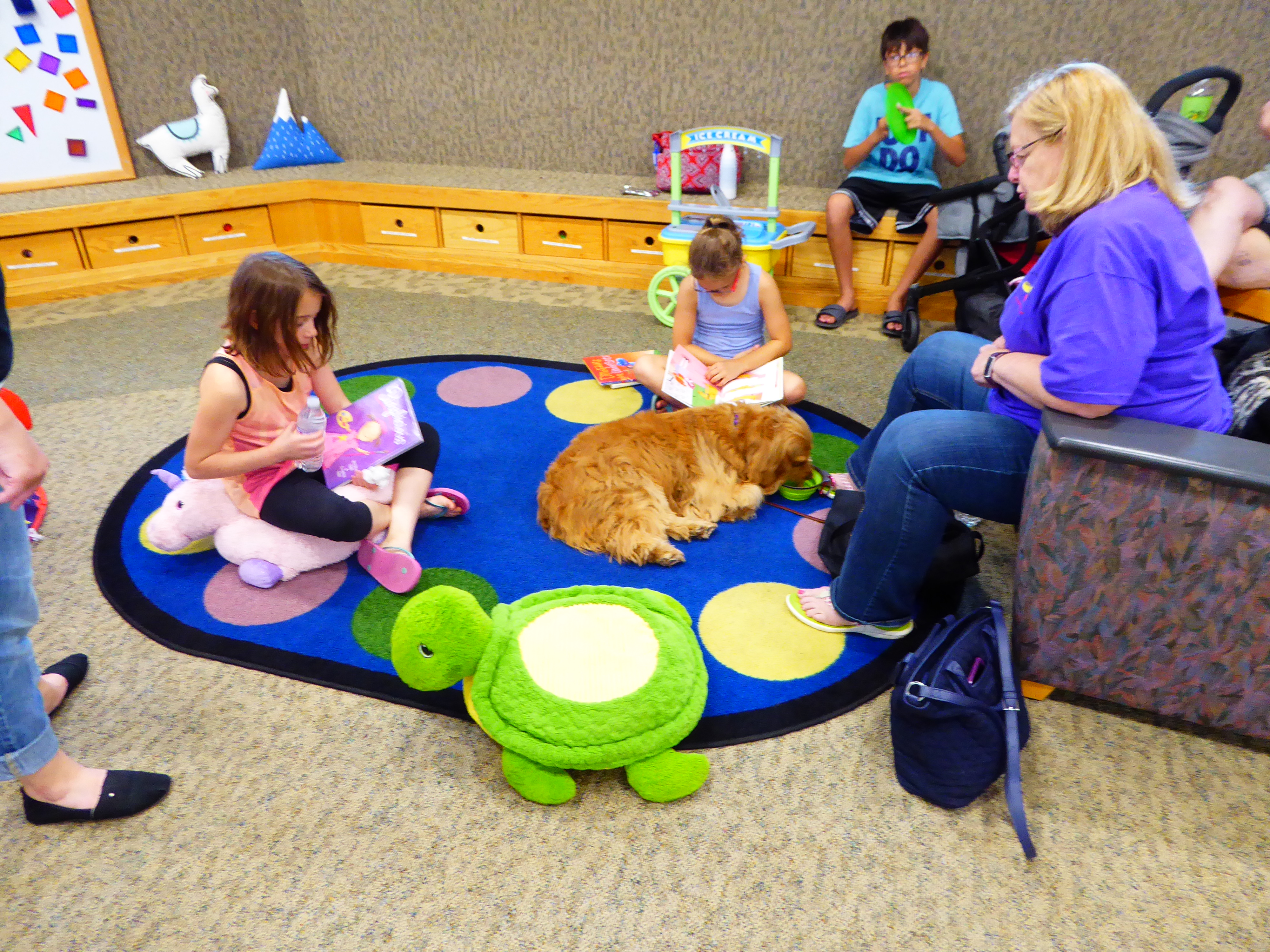 Kids practicing their reading skills with a dog from PAWS.