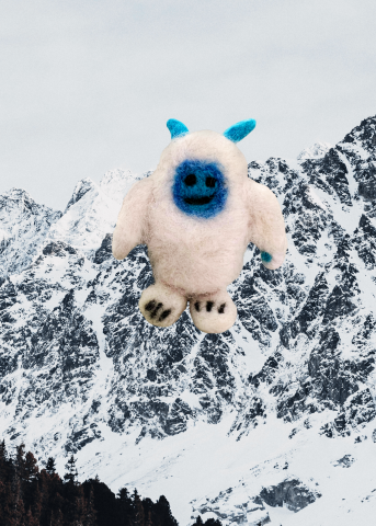 Needle Felted Yeti standing tall against a snowy mountain background