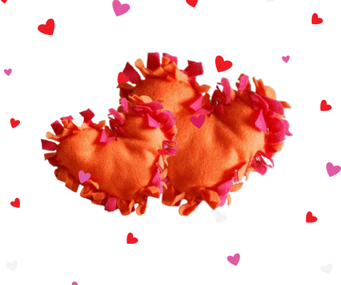 Two orange and pink pillows side-by-side against a white background dotted with hearts.