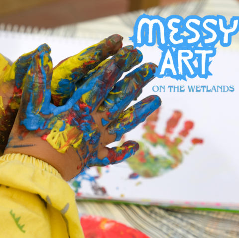 two toddler hands covered in colorful paints with a handprint on a paper in the background. the words messy art on the wetlands in blue in the top right corner