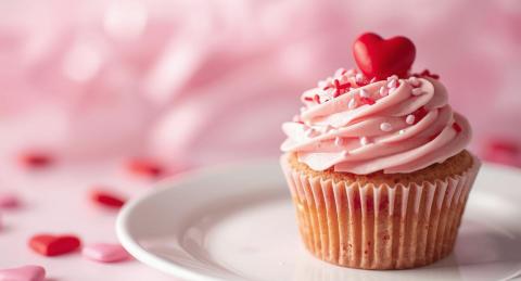Cupcake on a plate with Valentine's decorations on it.