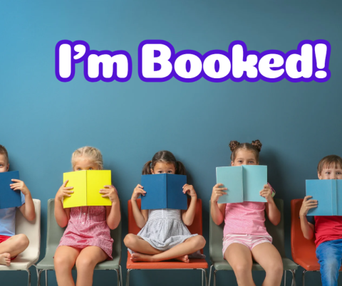 Purple words "I'm Booked!" against a blue background with a row of children sitting and looking over books below it. 