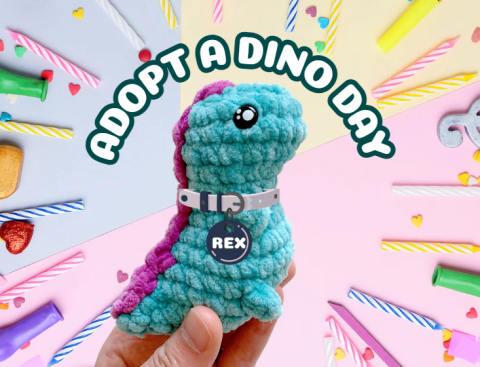 A crochet dinosaur, with the words "Adopt a dino day" above it. All around the image are different colored birthday candles, hearts, and confetti 