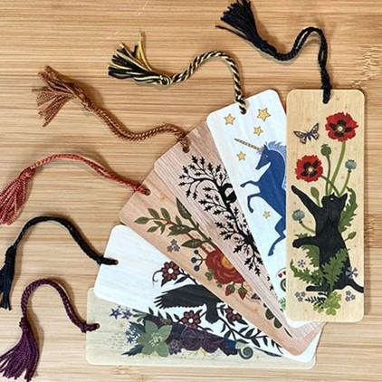 a brown wood background with and assortment of differently decorated bookmarks with tassles