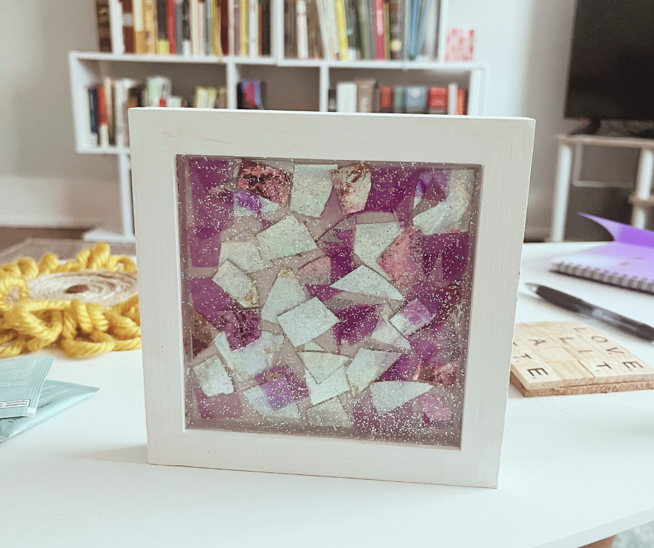 Mosaic made of broken cd's in a white wooden frame